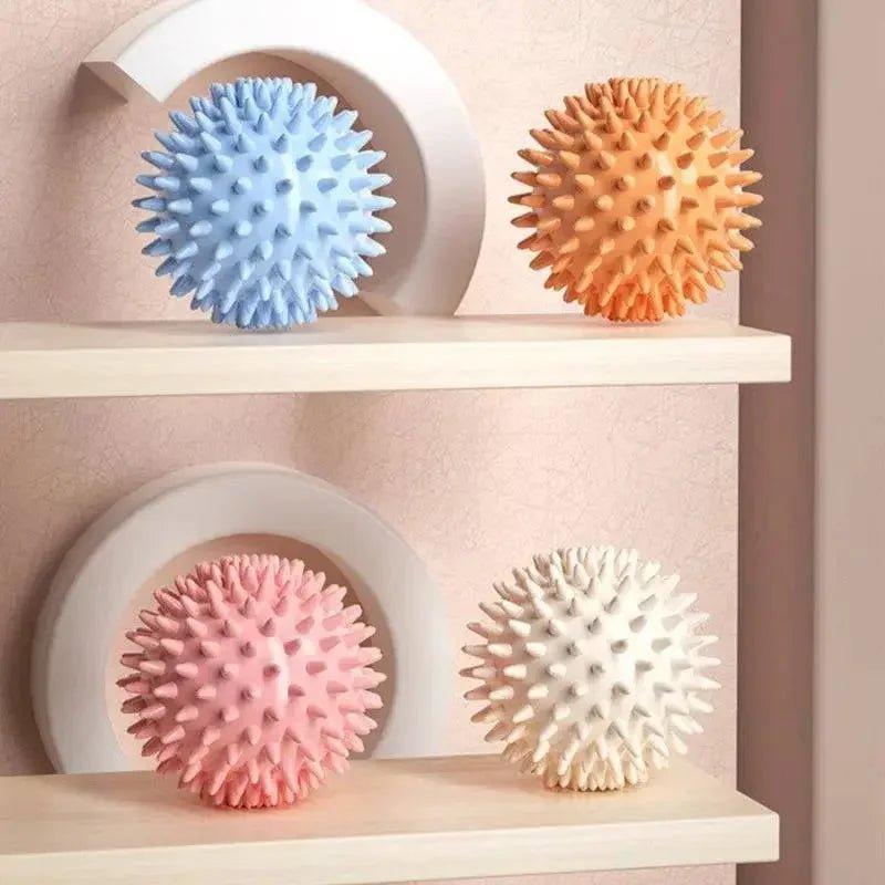 Spiky massage balls in pastel colors on wooden shelves for relaxation and muscle relief