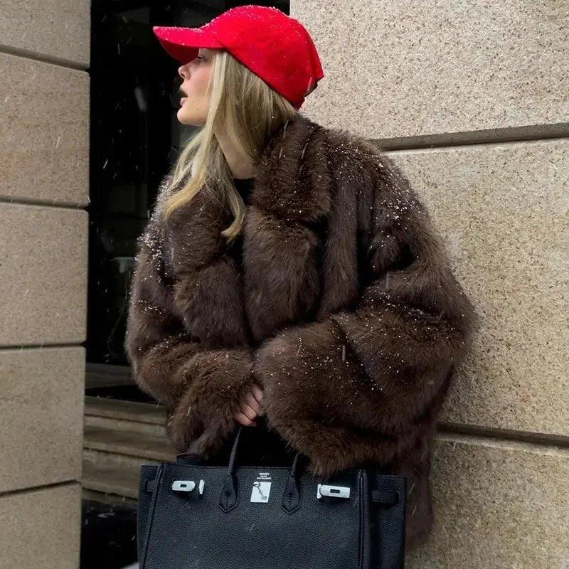 Woman in brown faux fur coat, red cap, holding black handbag, snowy urban fashion look