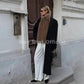 Woman in black coat with brown fur scarf, white pants, and sunglasses for street style fashion