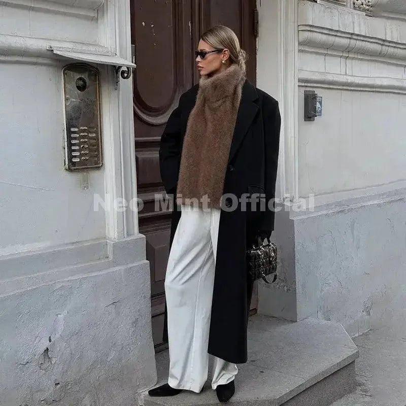 Woman in black coat with brown fur scarf, white pants, and sunglasses for street style fashion