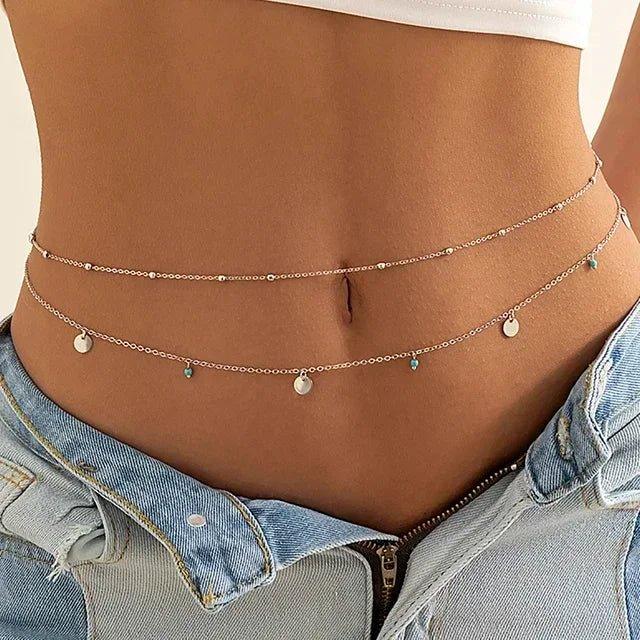 Layered gold belly chain with charms, worn with denim shorts and white top for women's fashion