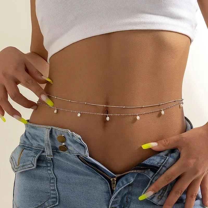 Woman wearing delicate pearl belly chain with white crop top and denim shorts, fashion accessory