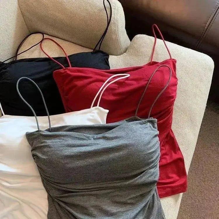 Women's ruched camisole tops in black, red, gray, and white, styled on a cozy armchair for casual fashion.