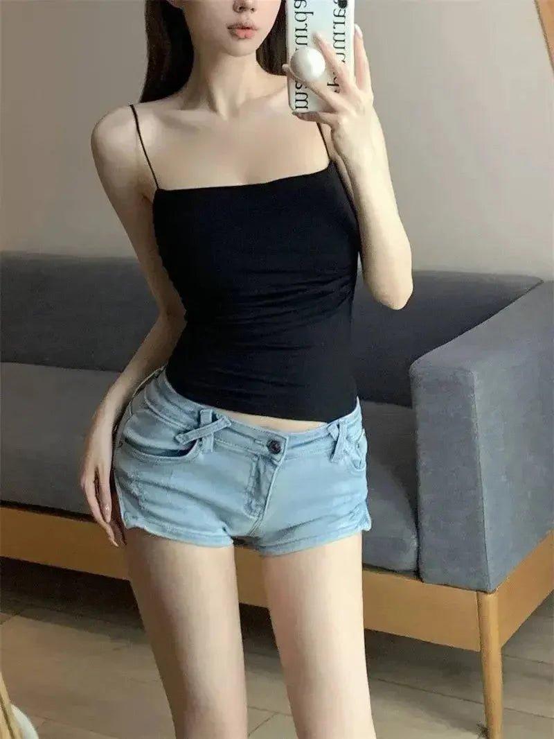 Woman in black spaghetti strap top and light denim shorts, casual summer fashion