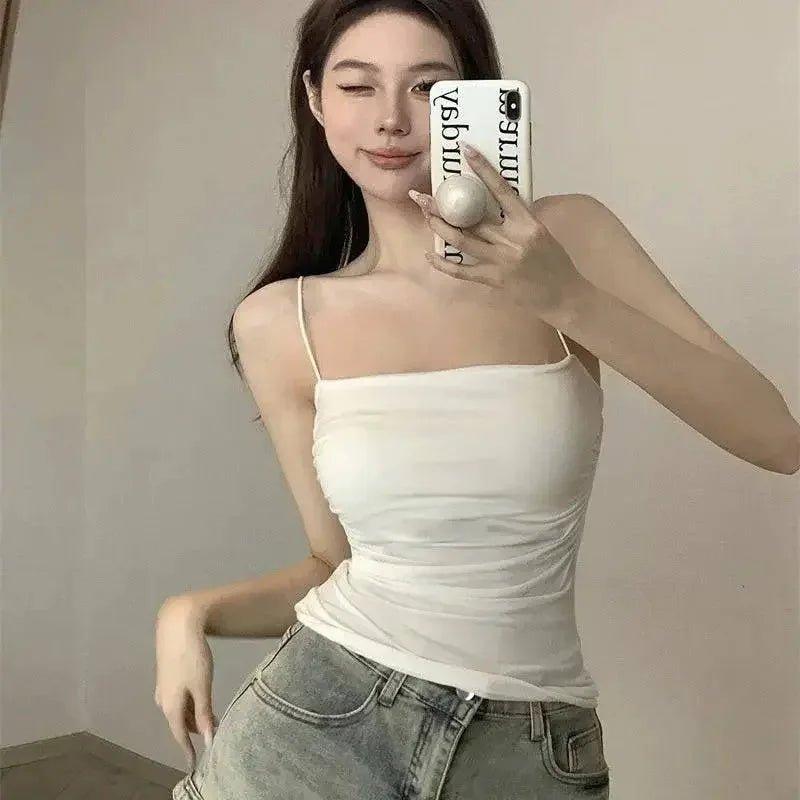Woman in white spaghetti strap top and denim shorts, stylish casual fashion