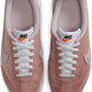 Pink Nike women's sneakers with white laces and orange swoosh, casual fashion footwear