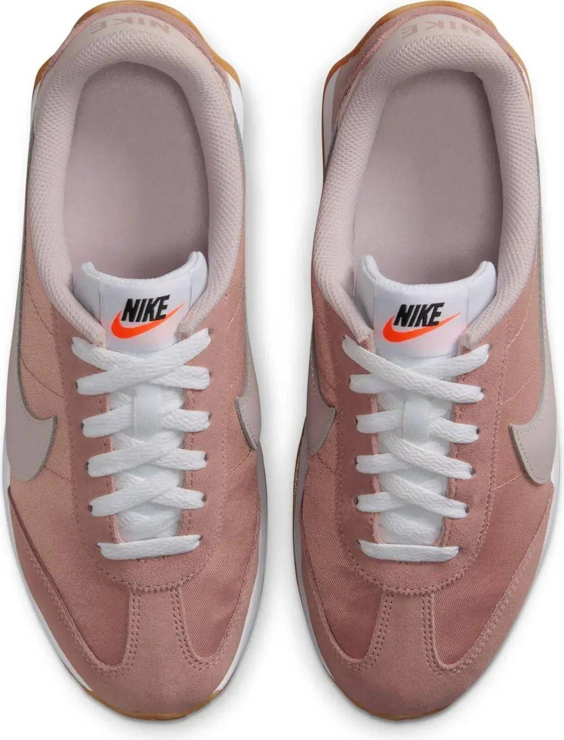 Pink Nike women's sneakers with white laces and orange swoosh, casual fashion footwear