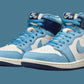 Nike Air Jordan 1 high-top sneakers in light blue, white, and navy with gold wing logo, stylish women's fashion footwear