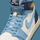 Nike Air Jordan 1 high-top sneaker in light blue, white, and navy with gold wing logo, fashion footwear