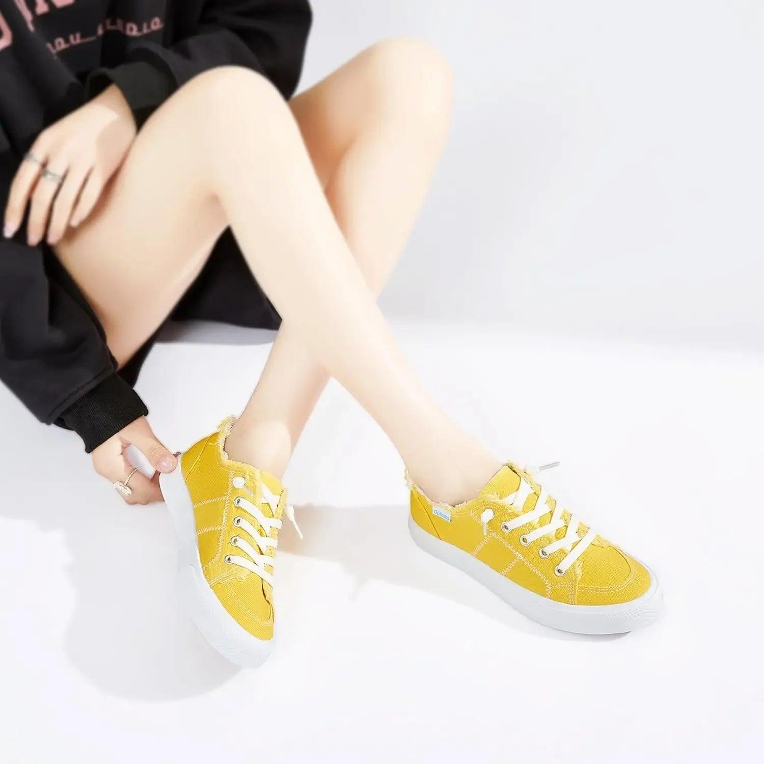 Bright yellow canvas sneakers with white laces, styled with black hoodie for casual women's fashion