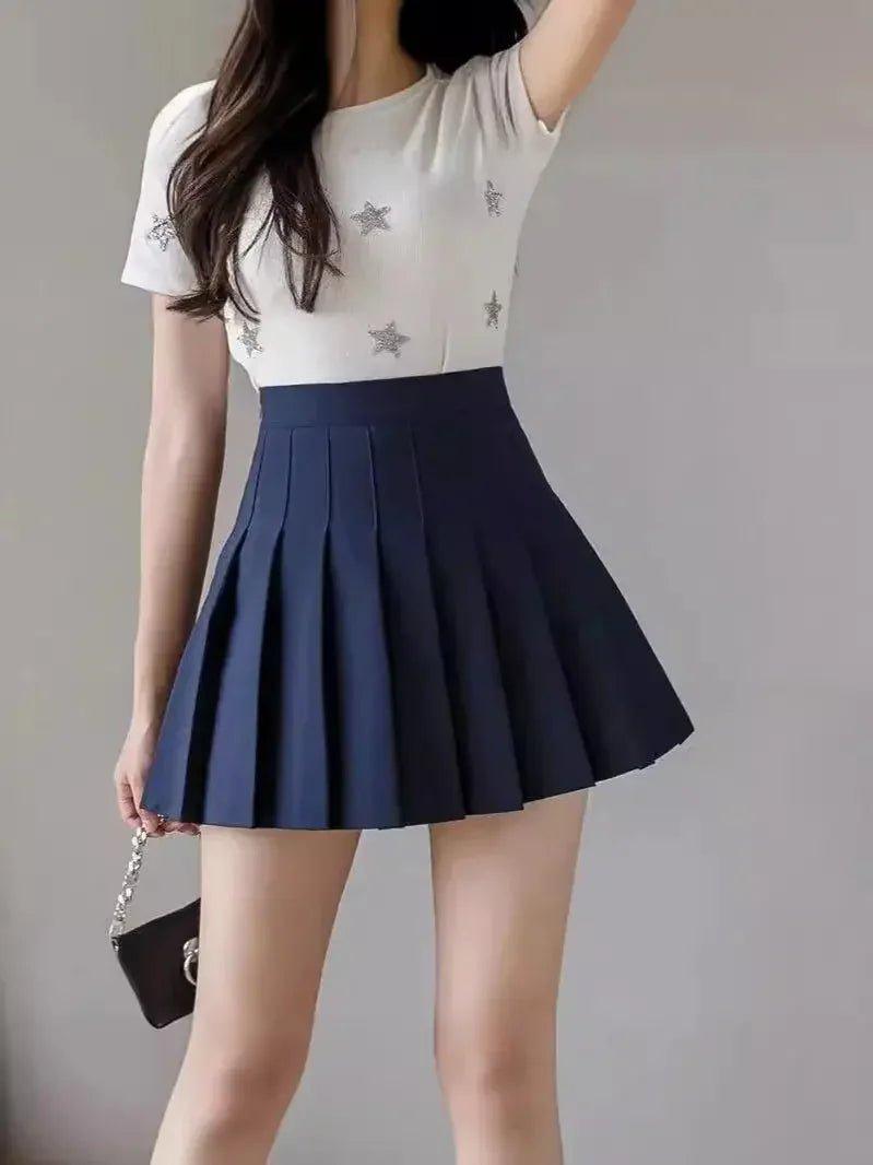 Woman in white star-print top and navy pleated mini skirt, fashion outfit