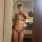 Woman taking mirror selfie in green and burgundy bikini, showcasing swimwear fashion