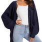 Navy blue chunky knit cardigan with buttons, styled over white top and light wash jeans for women's fashion