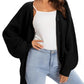 Woman wearing black knit cardigan over white top with light blue jeans, stylish fashion outfit