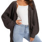 Woman wearing cozy brown knit cardigan over white top with light wash jeans, stylish fashion outfit
