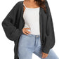 Woman wearing cozy black knit cardigan over white top with light blue jeans, stylish fashion outfit