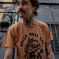 Man wearing 'Raise Hell Eat Tacos' graphic tee, tattooed arms, urban street style fashion