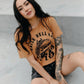 Woman in 'Raise Hell Eat Tacos' graphic tee, tattooed arms, black shorts, urban fashion style