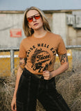 Woman wearing 'Raise Hell Eat Tacos' graphic tee, sunglasses, and black jeans, edgy street style fashion