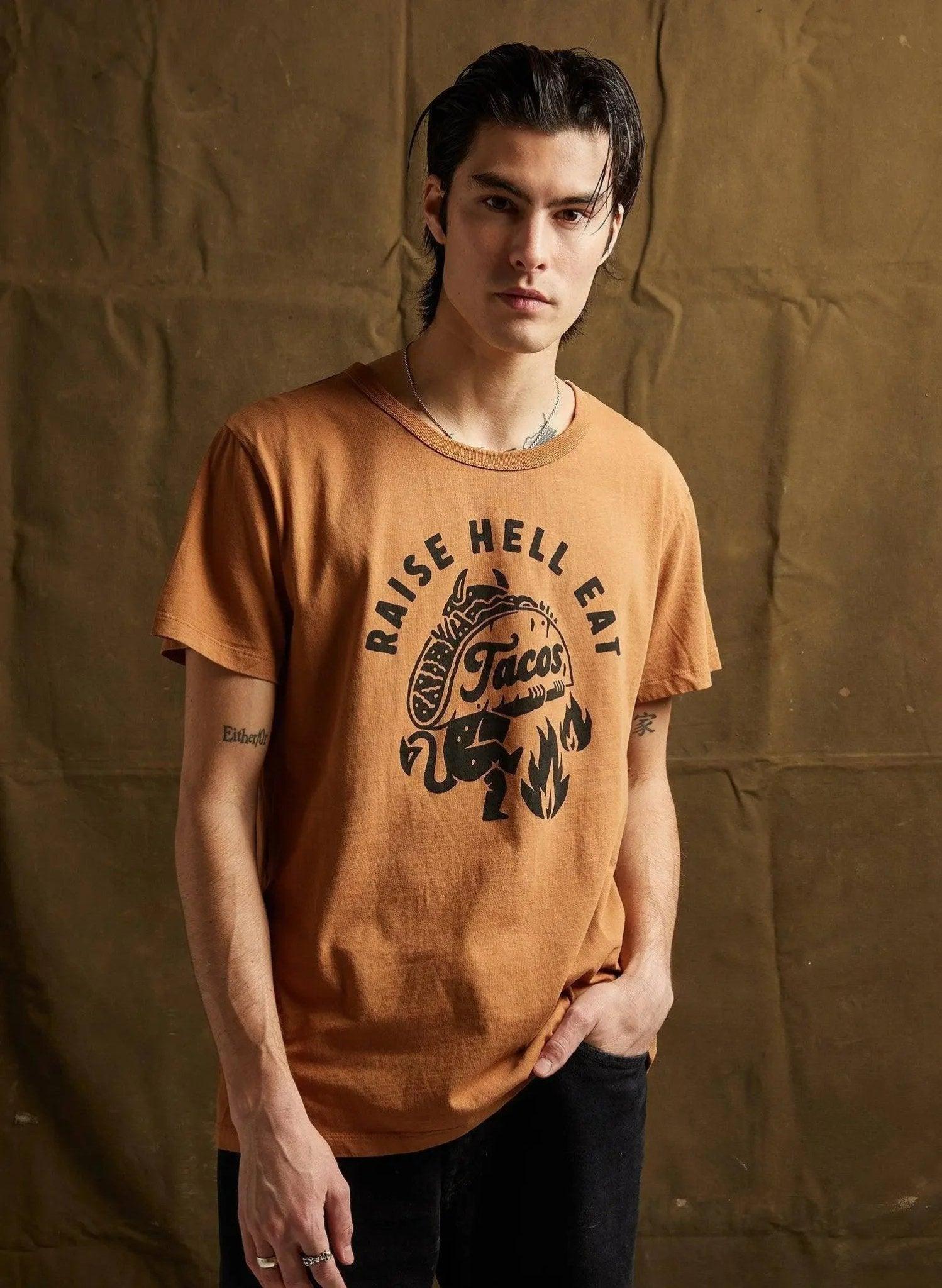 Men's orange graphic tee with 'Raise Hell Eat Tacos' print, casual streetwear style