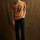 Man wearing orange graphic tee with 'Raise Hell Eat Tacos' print, black jeans, and loafers