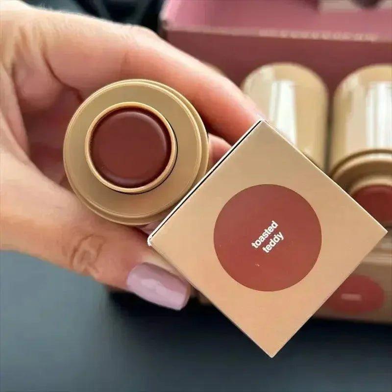 Hand holding toasted teddy lipstick with matching box, women's fashion beauty product