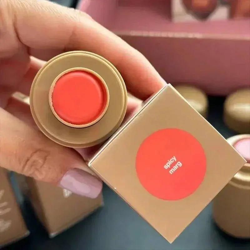Spicy Marg coral lipstick in gold tube, held with matching box, beauty makeup product