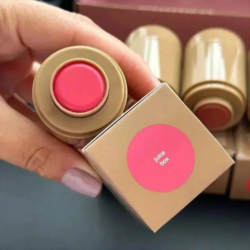 Hand holding pink juice box lipstick with gold packaging, beauty makeup product