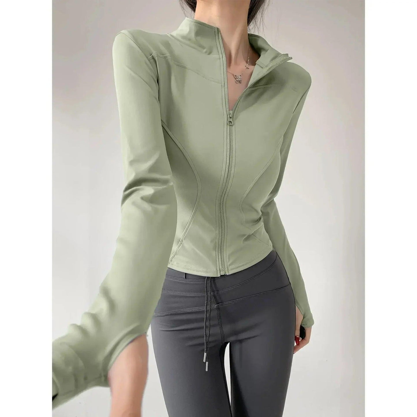 Woman in sage green zip-up fitness jacket and gray leggings, stylish activewear for gym or casual wear