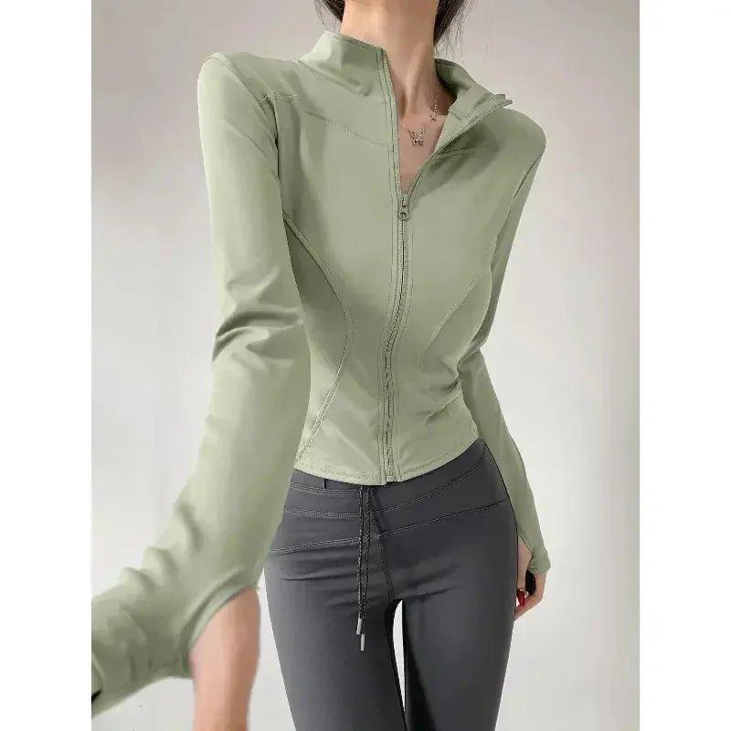 Women's olive green zip-up fitness jacket with long sleeves, paired with gray leggings for active wear.