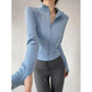 Light blue women's long sleeve zip-up athletic jacket with fitted design, paired with gray leggings