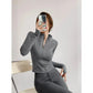 Woman in gray zip-up long sleeve activewear top and matching leggings, taking mirror selfie