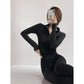 Woman in black long sleeve workout top and leggings, posing with phone for fitness fashion look
