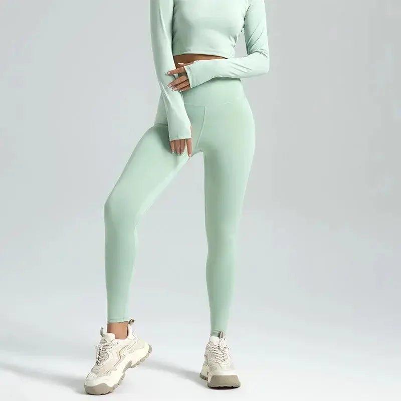 Mint green women's long sleeve crop top and high-waisted leggings with white chunky sneakers