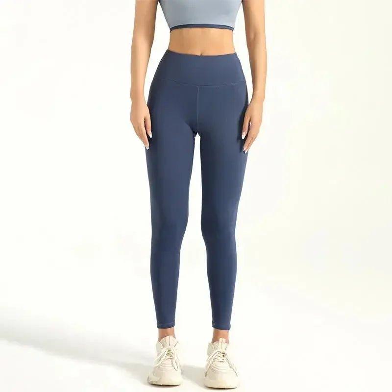 Woman wearing high-waisted navy blue leggings with gray sports bra and white sneakers