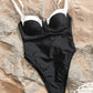 Black and white one-piece swimsuit with underwire bust on sandy beach, beach fashion