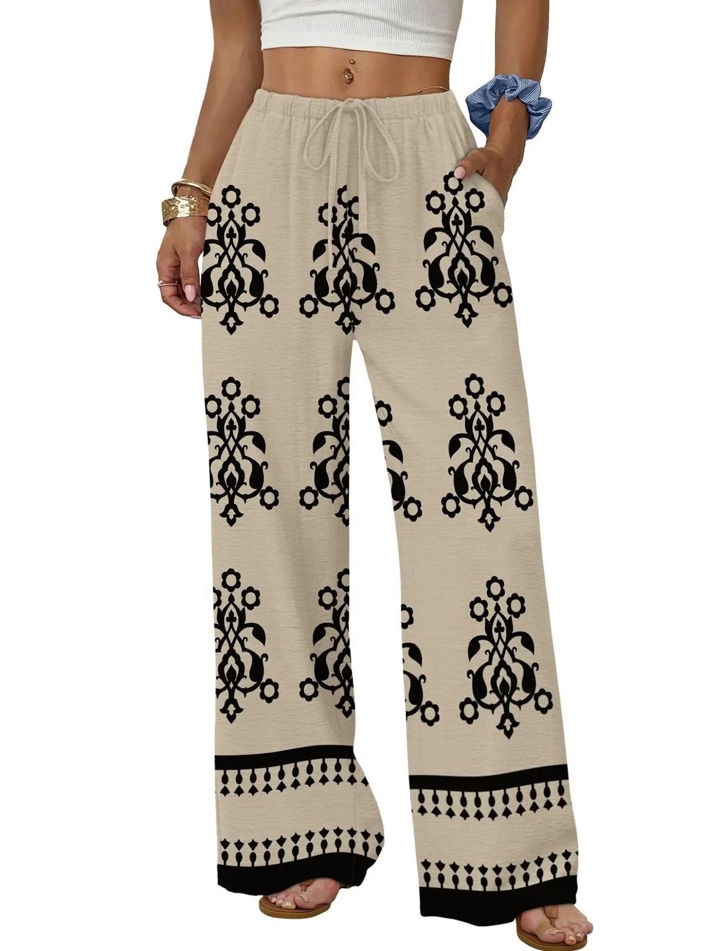 Women's beige wide-leg pants with black floral print, drawstring waist, and boho hem detail