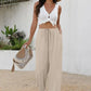 Woman in white knot crop top and beige wide-leg pants with straw hat and fringe bag, summer fashion outfit