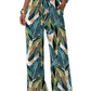 Women's tropical leaf print wide-leg pants with drawstring waist, paired with white crop top and sandals
