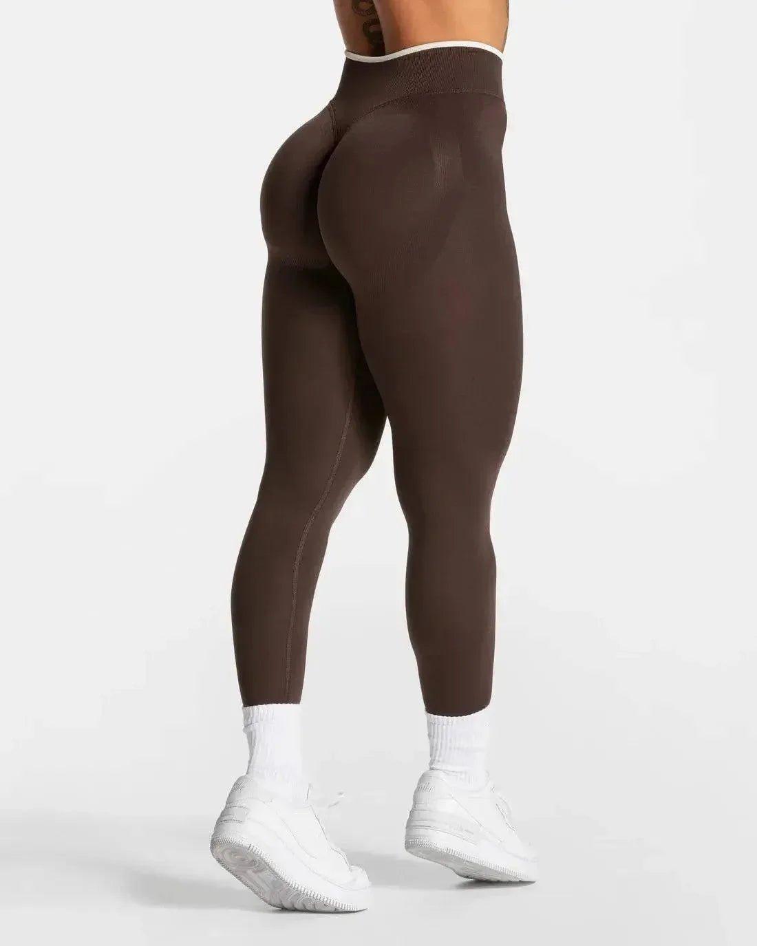 Brown high-waisted leggings with white trim, paired with white sneakers and socks, ideal for women's fashion and fitness.