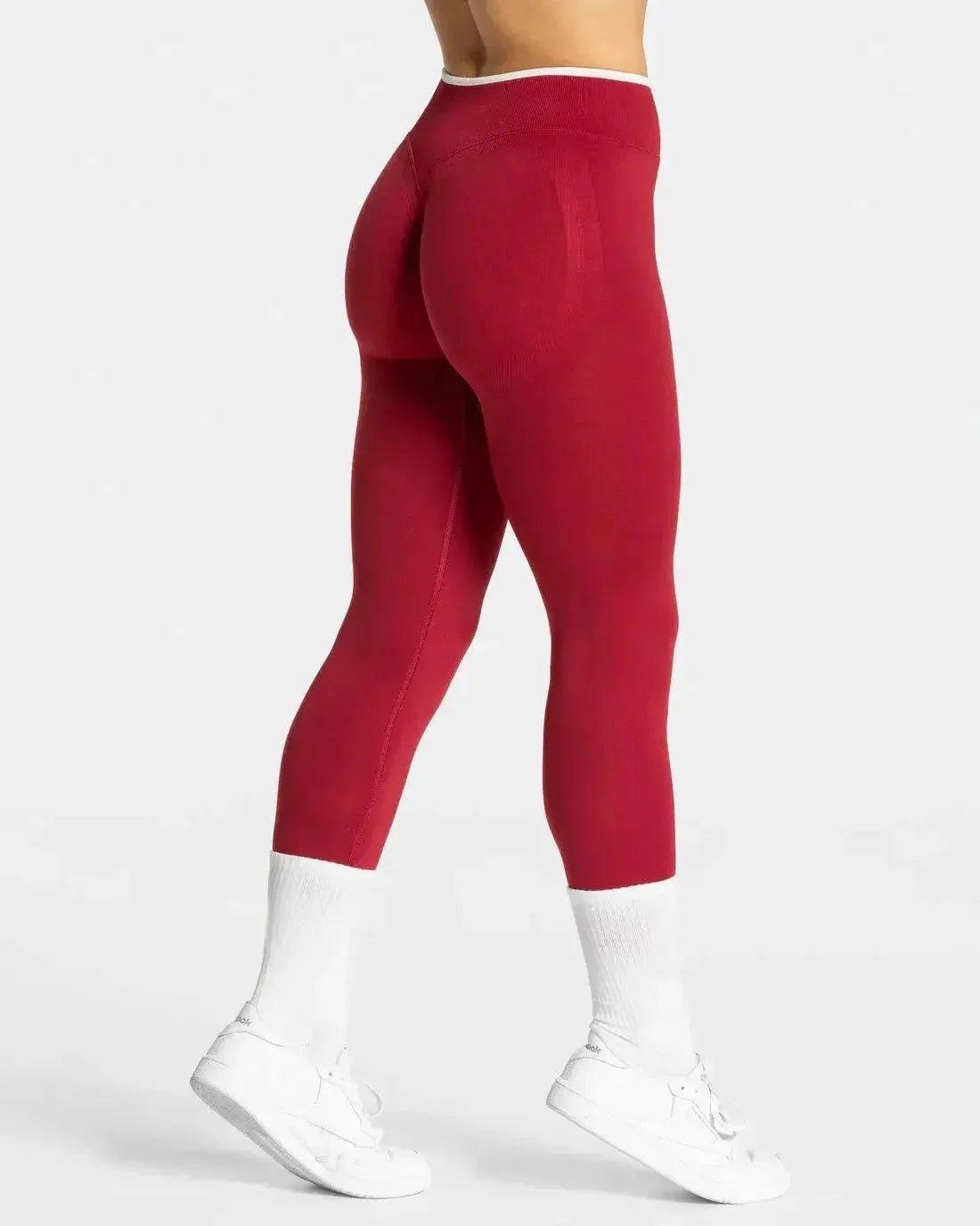 Red high-waisted leggings with white trim, paired with white sneakers and socks, ideal for women's fashion and fitness.