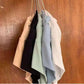 Women's fashion tops in pastel and neutral colors hanging on hangers against wooden background