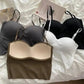 Women's seamless bras in black, white, gray, and beige, styled on white bedding with fashion magazine