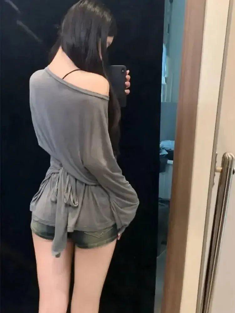 Woman in gray off-shoulder top and denim shorts taking mirror selfie, fashion outfit