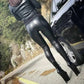 Woman in black leather leggings and high heels beside a car