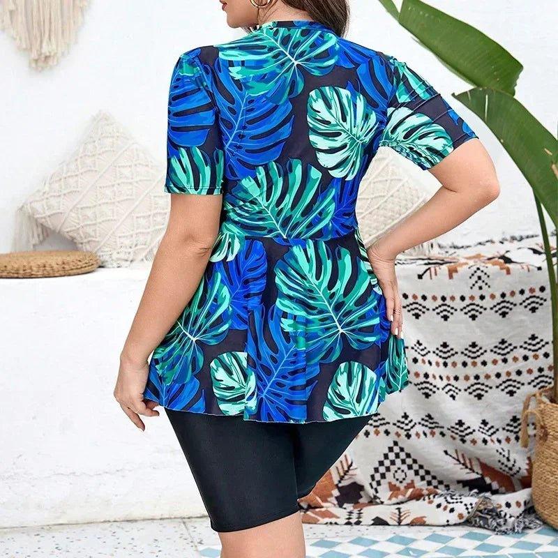 Woman wearing blue tropical leaf print swim cover-up top with black shorts, beach fashion style