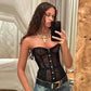 Woman in black lace corset top with gold buttons, layered necklaces, and jeans, taking mirror selfie