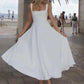Woman twirling in elegant white midi dress, beachside fashion