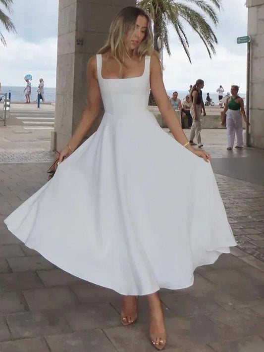 Woman twirling in elegant white midi dress, beachside fashion