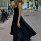 Woman in elegant black midi dress walking on city street, fashion style